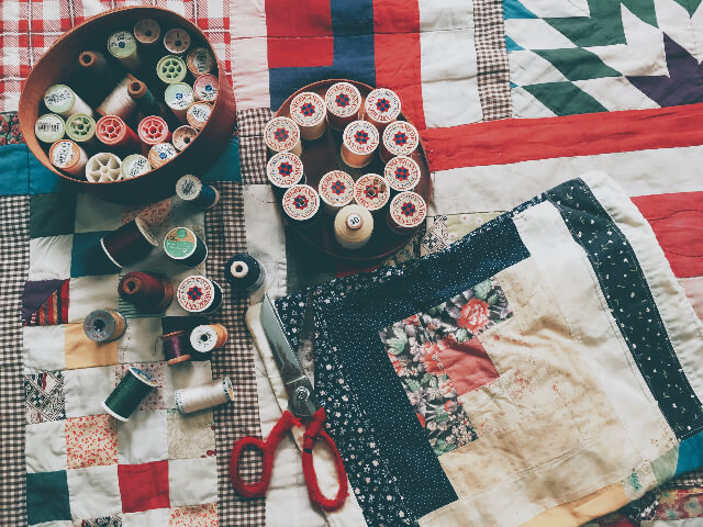 Spools of thread and a pair of scissors lying on a quilt top